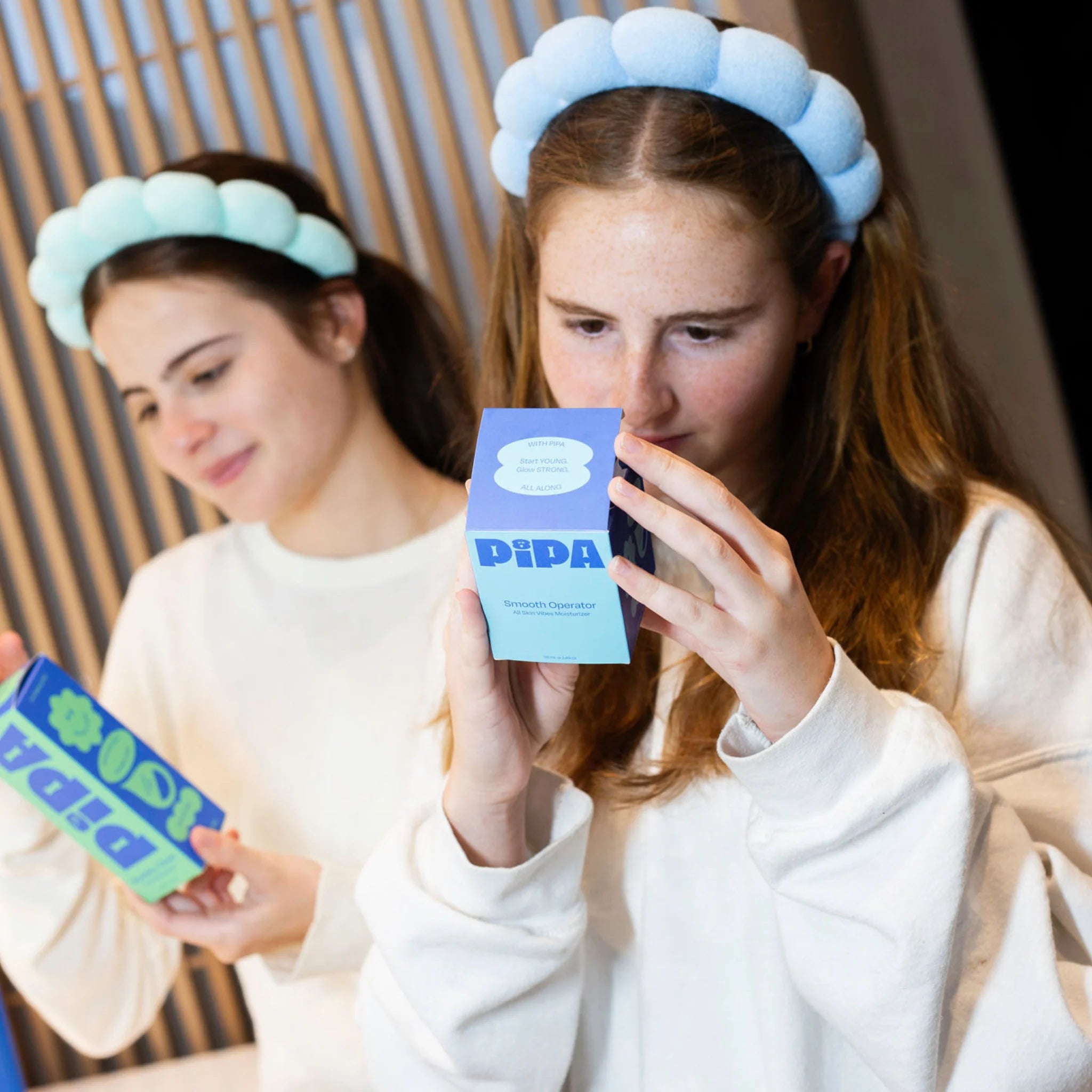 Tween girls reading ingredients of Daily Glow Bundle for skincare routine.
