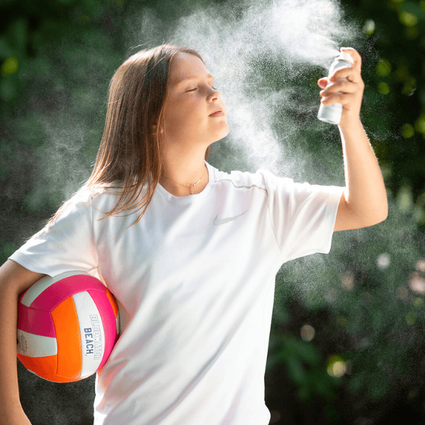 Tween using Skin Saver spray outdoors with volleyball