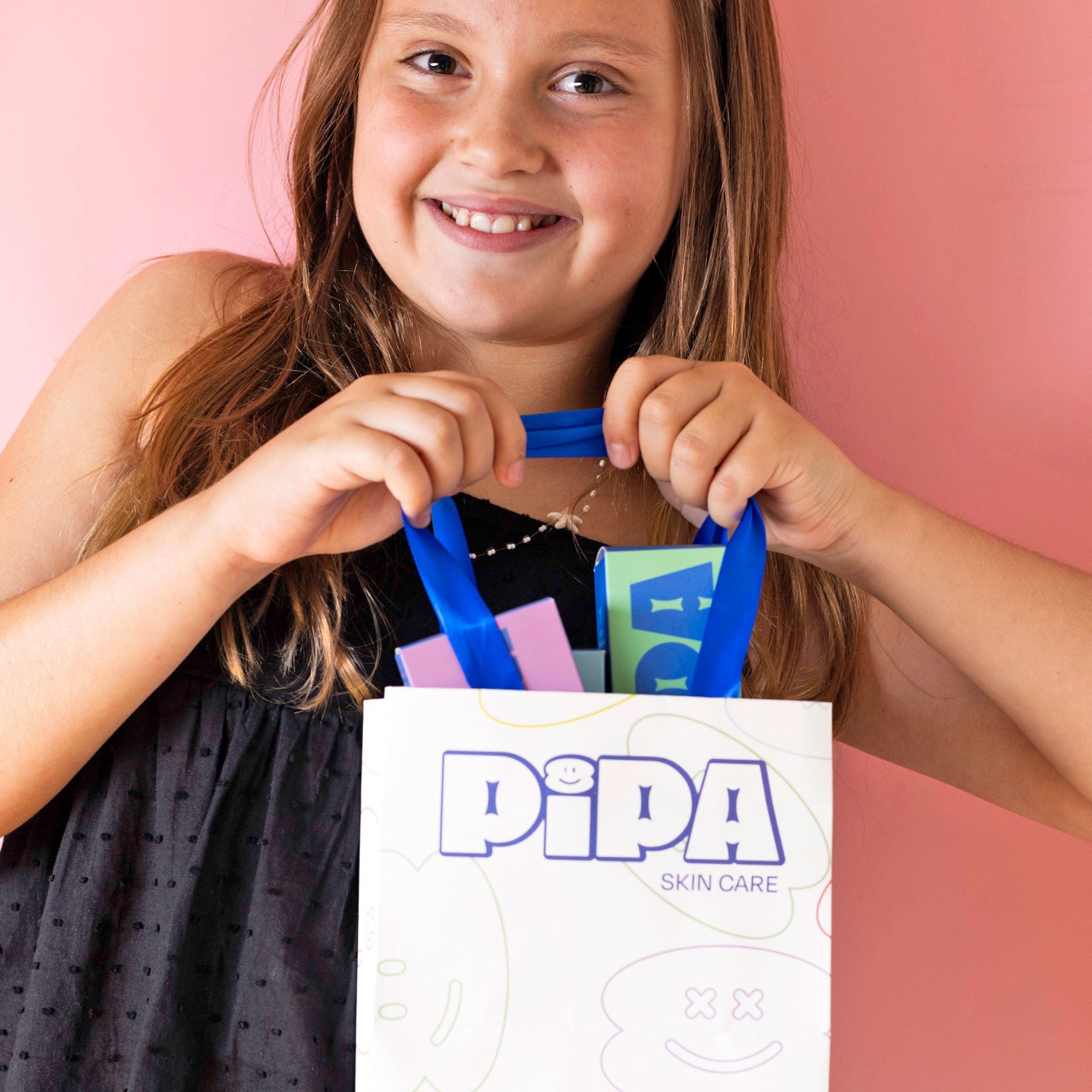 Child holding Pipa Gift Bag with ribbon handles, showcasing decorative paper design.