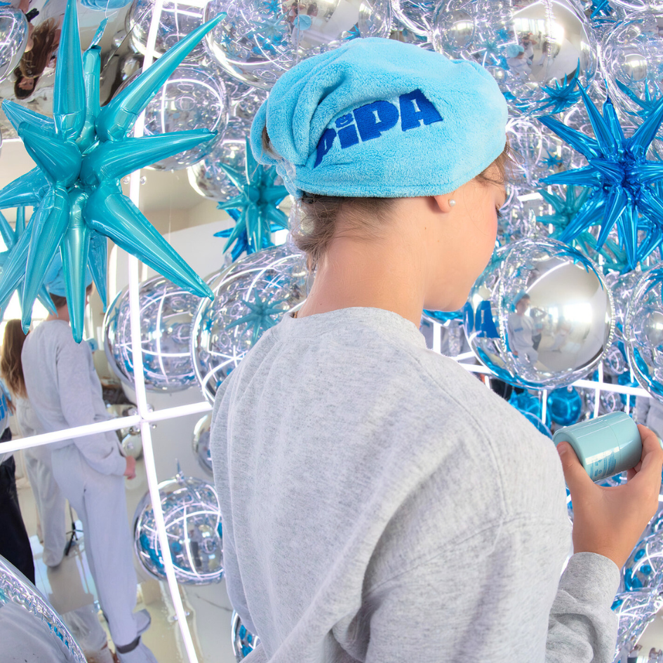 Person wearing blue Pipa Hair Towel in a reflective room with silver and blue decorations