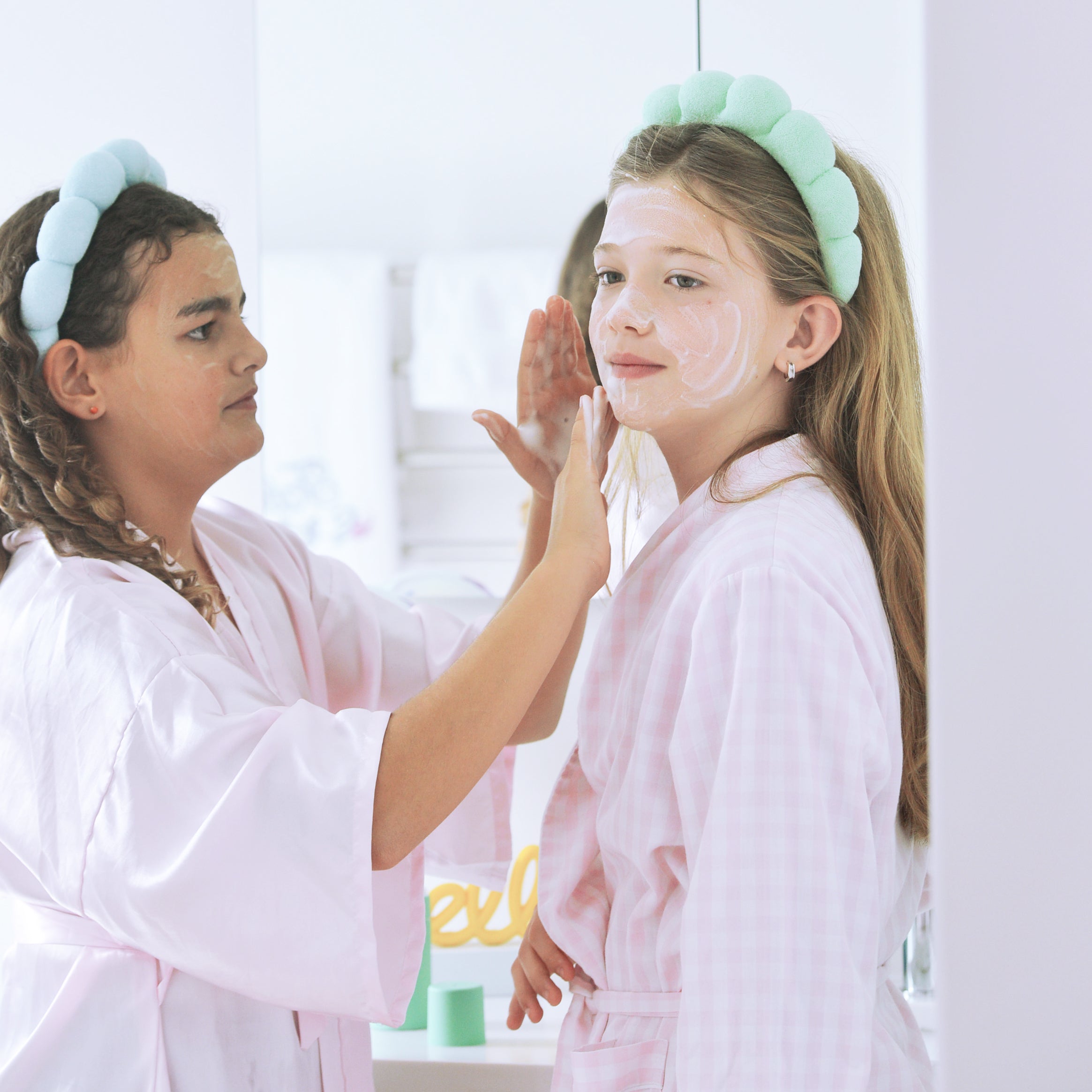 Kids wearing Pipa spa headbands and robes during a skincare routine.