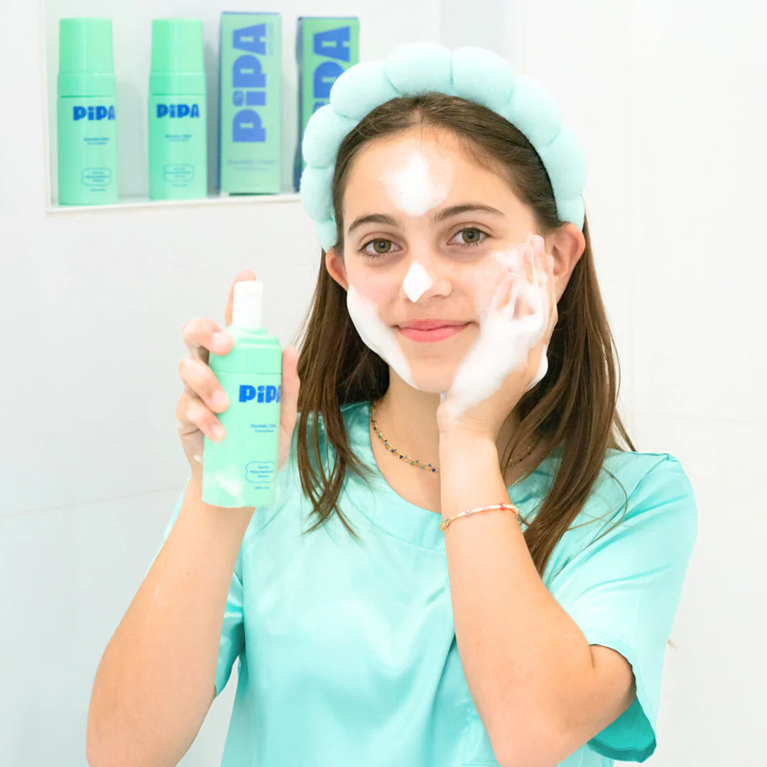 Tween using Squeaky Clean facial cleanser with foam on face and holding the product.