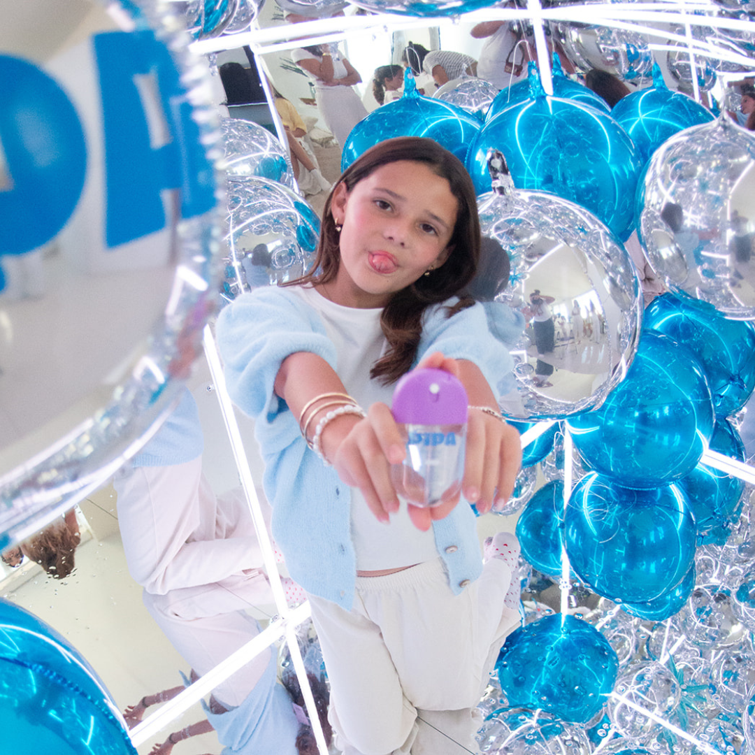 Tween girl holding Glow Go mist spray with reflective blue balloons background